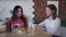 Two american woman drinking coffee and talking at table in kitchen interior.