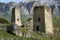 Two ancient Ossetian defensive towers against the backdrop of the Caucasus mountains