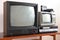 Two antiquated vintage TVs with VCRs sit on a vintage table in a tenement building from the 1990s, 1980s.