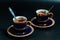 Two antique enamel cobalt gold rimmed cups of coffee  on a black background