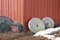 Two antique millstones leaning against a rustic red wooden build