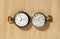 Two of antique silver pocket watches with golden clockwork on beige background. Retro mechanical watch with white dials