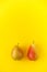 Two appetizing ripe pears with red side on a yellow background.