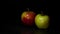 Two apples on a dark background. A drop of water flows down the apple.