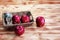 Two apples and dried flowe put in woven basket,beside blurred red apple