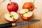 Two apples, halves of apple, knife on wooden table