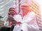 Two Arabic muslim wear white shirt humble sitting at front modern office discussing work with tablet and use the smartphone