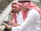 Two Arabic muslim wear white shirt humble sitting at front modern office discussing work with tablet and use the smartphone