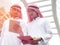 Two Arabic muslim wear white shirt humble Standing at front modern office discussing work with tablet