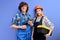 Two architects in uniform coveralls stand with tools instruments posing isolated on blue