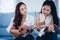 Two asia women are having fun playing ukulele and smiling at ho