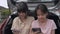 Two Asian adorable teen girls enjoy watching social video online on mobile smartphone with earphones.