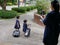 Two Asian baby girls pulling their new trolley school bags while being photographed by her mother