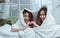 Two Asian beautiful adorable LGBT lesbian women lying down on bed, smiling with happiness and love under white comfortable blanket