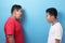 Two Asian boys screaming shouting at each other against blue background