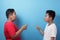 Two Asian boys screaming shouting at each other against blue background