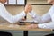 Two asian business people looking at each other eye and play wrestling on the table