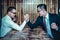 Two Asian businessman expressed a serious expression and fighting by used arm wrestling on wood table.