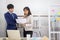 Two Asian businessmen and women stand and speak in the office in the hand with the documentation