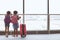 Two asian child girls with backpack looking at plane and waiting for boarding in the airport together