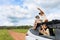 Two asian child girls in car and sitting on car roof with their father looking through binocular searching for animal