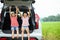 Two asian child girls sitting in a car trunk and raise their hand with happiness while going on vacations with their parents.