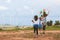 Two asian child girls and their mother are running and playing with wind turbine toy together in the wind turbine field