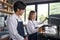 Two asian coffee waitress making cup of hot coffee latte in coffee shop cafe. Barista working with coffee machine in shop. The