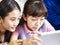 Two asian elementary schoolgirls using digital tablet together