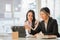 Two Asian female accountants working in the office with laptop computers and financial documents on the table.