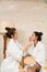 Two Asian female friends chat while waiting in the spa reception area