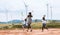 Two asian girls and their mother are running and playing with wind turbine toy together with fun in the wind turbine field