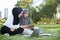 Two Asian Islamic female students sitting in the garden with their laptops while doing their homework