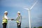 Two asian male engineers handshake with wind turbine and clear blue sky on the background