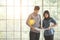 Two Asian male and female engineers holding white and yellow safety helmet standing and talking together