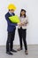 Two Asian male and female foreman wearing a helmet and standing and talking at the event site