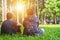 Two asian man friends sitting on green grass in the park, encouraging, comforting his friend and looking in the same direction