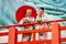 Two Asian pretty women stay close to red railing in the area of base of green big buddha statue also look at camera with smiling