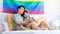 Two Asian pride male gay men lover couple partner sitting smiling laying down cuddling hugging holding hands together on bed in