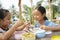 Two asian woman eating food together from pinto box container