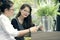 Two asian woman with smart phone in hand talking  in home living room with happiness face