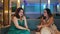 two Asian women gossiping in a hotel chair with lively faces