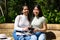 Two Asian women on holiday. They are sitting in a park looking at the pictures on the camera. On her legs she is holding a tourist