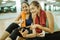 two asian women sitting while using mobile phone post workout