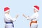 Two athletes in caps of Santa Claus standing in rack of karate