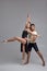 Two athletic modern ballet dancers are posing against a gray studio background.