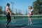 Two athletic young women play tennis on an outdoor court on a hot summer day. The girl defeated her tennis rival.