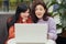 Two attractive astonished girls sitting in front of white laptop and checking sales results, being astonished and posing with