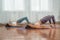 Two attractive athletic girls train asana yoga pose on mats on a light background. A group of young women stretch out in