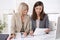 Two attractive businesswoman sitting in an office working in a t